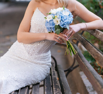Bride holding wedding bouquet sitting on bench