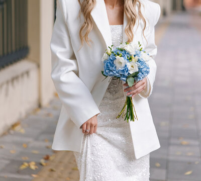 Bride holding wedding blue and white bouquet outdoors