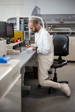 Male scientist writes notes at a desk in a high-tech laboratory