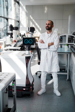 Male researcher stands with a robot in a modern laboratory