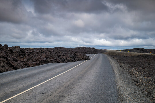 Cooled basalt lava flow blocks the asphalt road in Iceland
