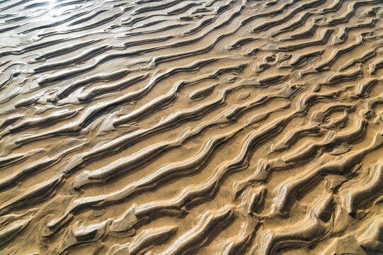 Wet sand forms abstract ripple patterns on a beach in Fuerteventura