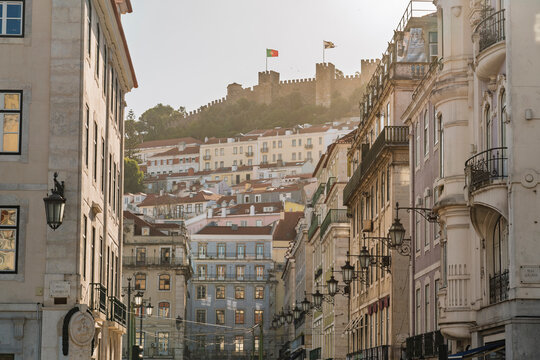 A historic downtown street reveals the Lisbon cityscape and castle