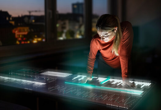 Woman analyzes data on a futuristic office screen at night