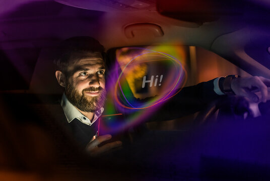 Young man interacts with AI chatbot on mobile phone in car at night