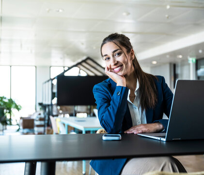 Smiling businesswoman uses a notebook in the modern office