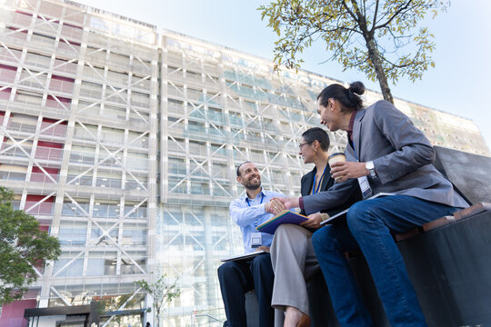 Three business colleagues shaking hands outdoors