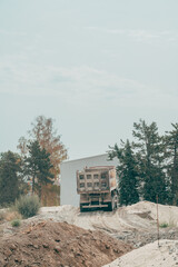 Heavy dump truck operating on dirt mounds during roadwork. Concept of infrastructure development, earthmoving operations, construction machinery, and industrial transport. © Bits and Splits