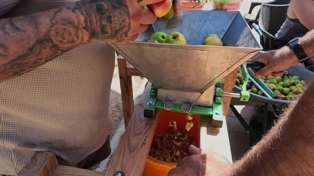 Men Crushing Apples in Hand-Crank Grinder in Slow Motion Today