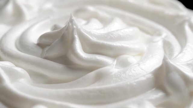 Delicious and airy white whipped cream rotating in a seamless loop, revealing its delicate and smooth texture in a beautiful macro view perfect for confectionery and pastry concepts