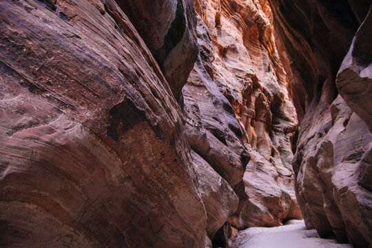 Natural rock formations in narrow slot canyon with sand path in Utah