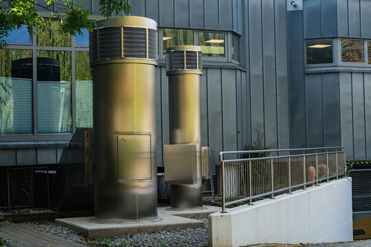 Two cylindrical vent pipe structures near a building in an urban area