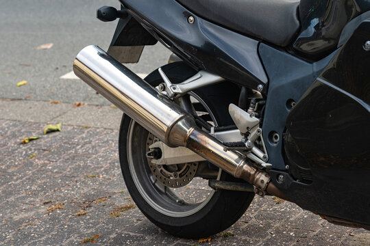 Closeup of motorcycle exhaust pipe on a street surface