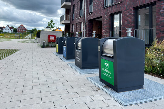 Modern recycling bins line the pathway in a residential area