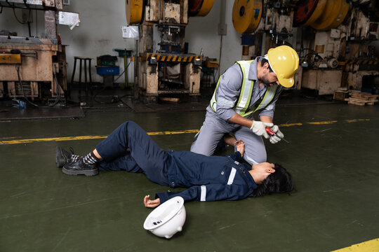 Engineer woman with hurting lying on the floor and male worker in safety helmet helping and calling ambulance