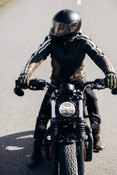 Biker wearing a black helmet and leather jacket, sitting on a vintage-style motorcycle, ready for adventure on the open road