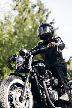 Biker wearing leather jacket and full face helmet riding vintage style motorcycle outdoors, enjoying freedom and adventure