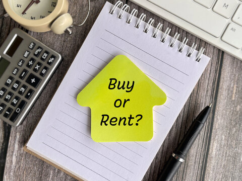 Yellow house-shaped note reading &ldquo;Buy or Rent?&rdquo; on a spiral notebook, illustrating real estate, housing, property investment, and financial decisions.