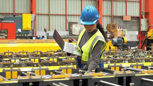 Female Engineer Inspect Automated Factory Machinery With Laptop : Professional Asian female technician hardhat check industrial roll forming line use laptop computer in manufacturing plant.