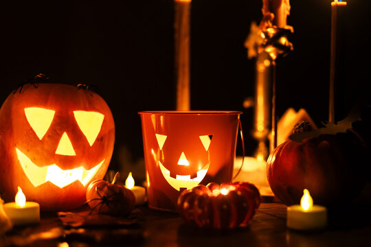 Happy Halloween. Carved glowing halloween pumpkins, burning candles and spooky spiders in dark. Atmospheric halloween night with jack o lantern decorations. Boo. holiday banner