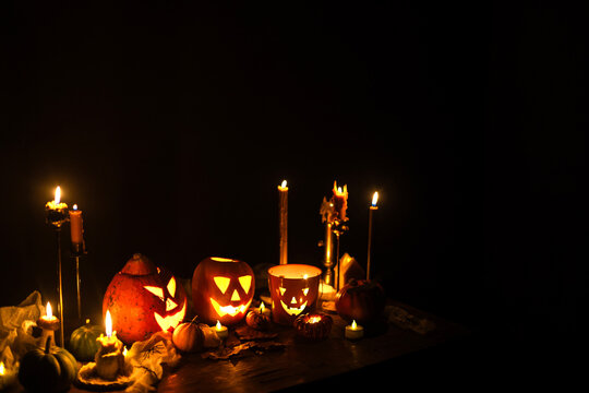Happy Halloween. Carved glowing halloween pumpkins, burning candles and spooky spiders in dark. Atmospheric halloween night with jack o lantern decorations. Boo. holiday banner
