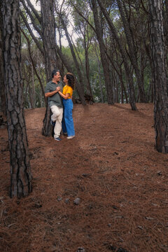 Smiling couple holding hands beside a pine tree with forest copy space