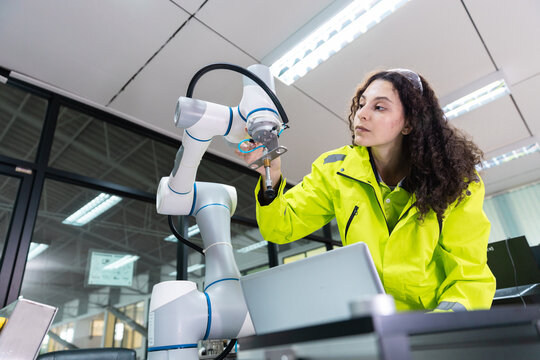 Female engineer closely inspecting and adjusting robotic arm components in high-tech industrial environment, symbolizing precision, innovation, smart automation.