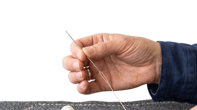 Hand holding sewing needle with thread isolated on white background