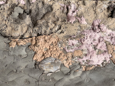 Weathered concrete wall with peeling pink and gray paint texture.