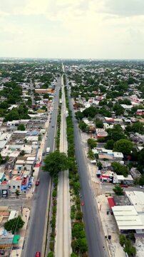 Aerial drone shot flying over a long straight avenue in a developing city