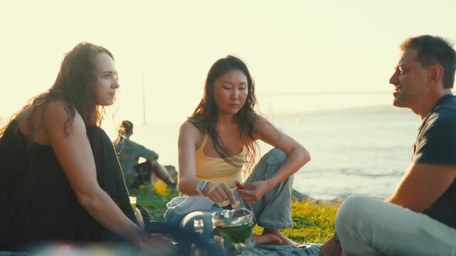 Diverse friends enjoying a sunny picnic by the sea
