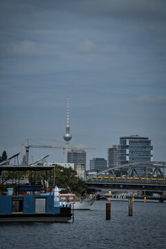 Berlin Skyline with Television Tower, Spree River, and Bridge Under Cloudy Sky.