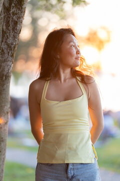 Asian woman enjoying golden hour sunset in park