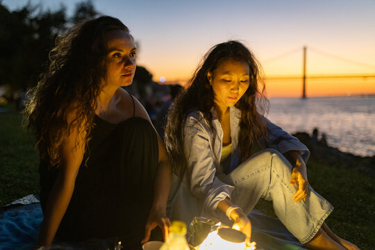 Friends enjoying picnic by tagus river at sunset