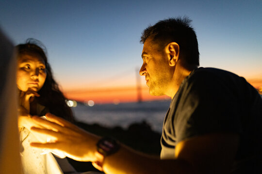 Couple having intimate conversation at twilight near bosphorus bridge