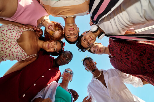 Diverse friends huddling together smiling looking down
