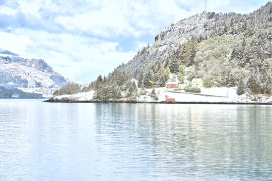 Idyllic Nordic Village at the Fjord with Snow-Covered Slopes.