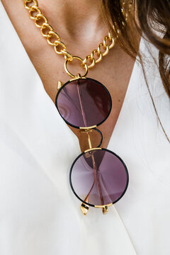 Collier cha&icirc;ne dor&eacute;e et lunettes de soleil port&eacute;es sur une chemise blanche
