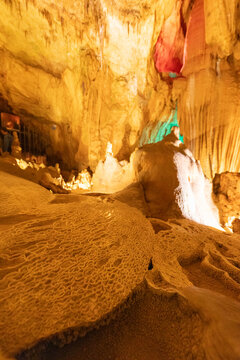 Stalactites and stalagmites in a brightly lit cave with interesting rock formations
