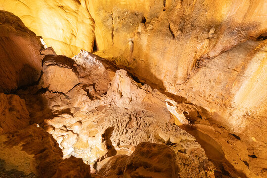 Exploration of a cave with rock formations and shadows in a dimly lit environment