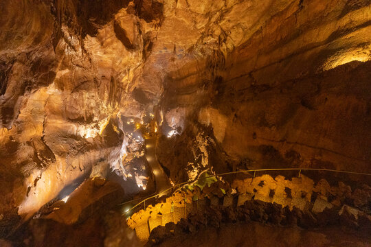 Exploring a cave with winding paths and lit formations in a natural underground environment