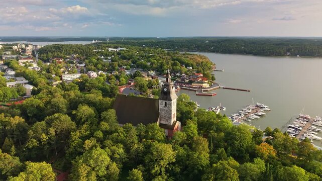 Aerial perspective of the medieval Naantali church nestled in green woods, Finland. Marina and coastal archipelago. Discover the beauty of Naantali church and its adjacent sailing harbor