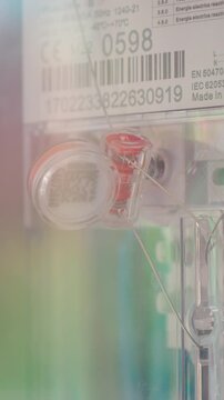 Vertical Screen: A close view of a seal on an electric meter during the installation. The meter is part of the electrical panel setup in a residential location.