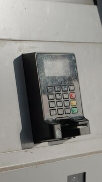 Vertical Screen: POS terminal is mounted on a wall outside. It faces the weather and is ready for wireless payments. The device is in use for quick transactions.