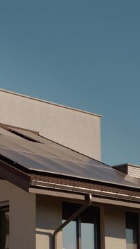 Vertical Screen: The roof of a house features several solar panels designed to harness renewable energy from the sun. This setup promotes clean energy use and sustainability.