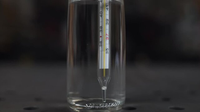 A laboratory worker inserted a mercury thermometer to the bottom of the bottle to measure the temperature of the liquid to be poured into it.