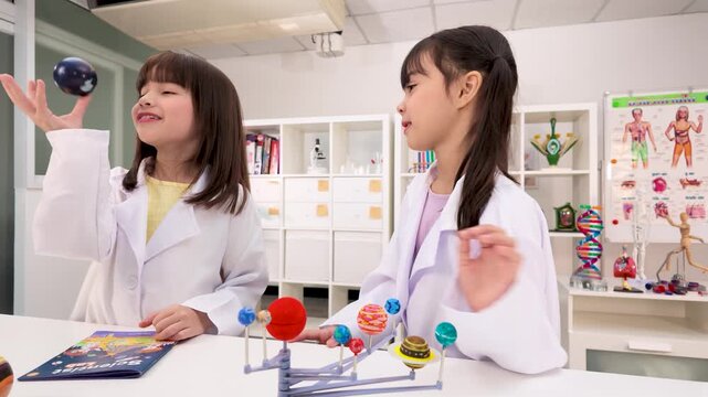 Elementary School Girls in Lab Coats Studying Solar System Model