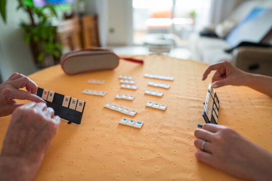 Senior and social worker play tile game together at home