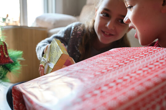 Siblings sharing joy and anticipation while unwrapping holiday presents
