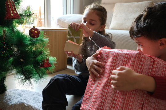 Children celebrating christmas receiving present at home